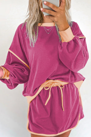 Contrast trim sweatshirt and skort set in red-violet with peach accents, drawstring waist, and balloon sleeves.