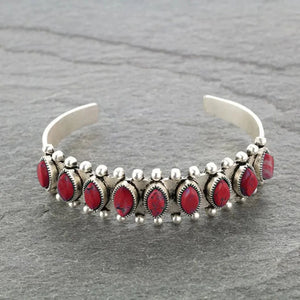 Silver open bangle bracelet with red cabochon stones and beaded details