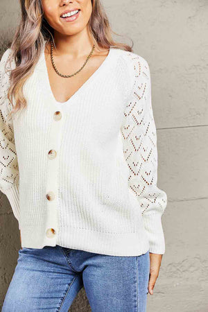 White diamond knit button-down cardigan with V-neck and openwork sleeves.