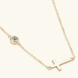 Gold asymmetrical cross pendant necklace with a bezel-set crystal accent.