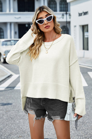 Cream acrylic sweater with flared sleeves and side slits, styled with denim shorts.