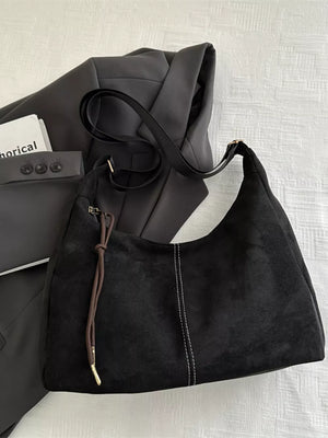 Black suede crossbody bag with adjustable strap and contrast stitching