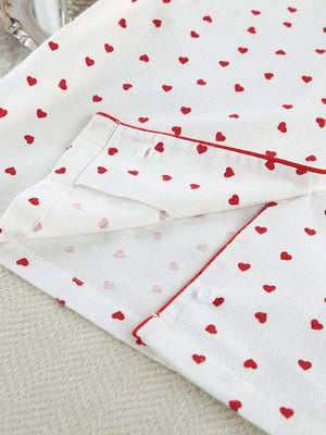 White cotton pajama set with red heart pattern and red piping detail.