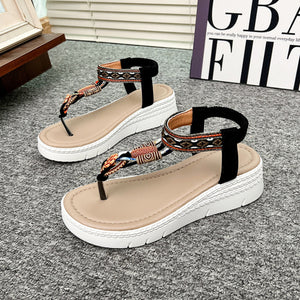 Ethnic-patterned wedge sandals with floral accents and ankle straps in black and khaki.