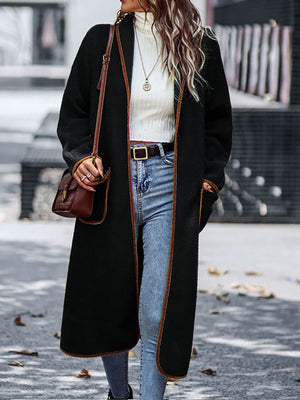Black teddy coat with contrast trim detailing and open front, worn with jeans.