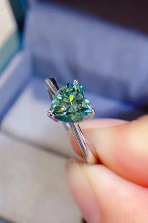 Green heart moissanite solitaire ring with a silver band.