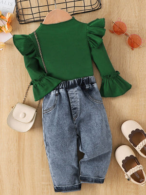 Green ribbed top with ruffle sleeves and bell cuffs paired with denim jeans with elastic waistband.