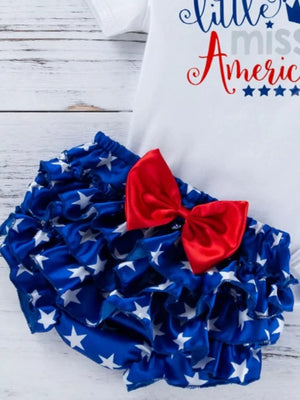 Baby outfit set with white top and ruffled bloomer shorts in blue with white stars and a red bow.