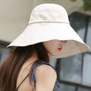 Beige cotton sun hat with wide brim and UV protection, featuring a decorative button detail.