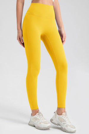 Yellow high-waist performance leggings with sculpting seams and a full-length cut.