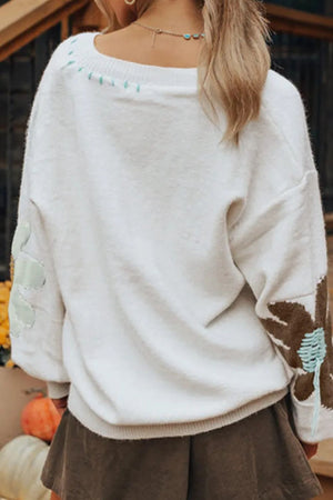 White knit sweater with embroidered floral details on sleeves and neckline