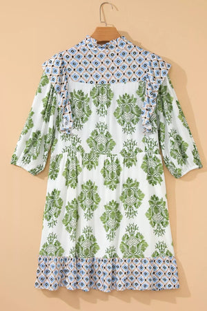 White mini dress with green floral print, ruffled neckline, and patterned hem.