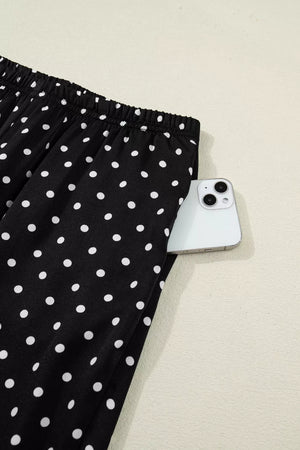 Black polka dot maternity wide-leg pants with a side pocket holding a smartphone.