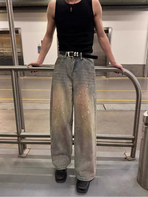 Vintage wash distressed wide-leg jeans with paint splatter detail and a black belt.