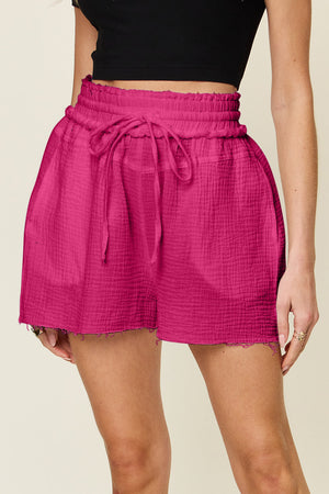 Hot pink textured gauze shorts with drawstring waist and frayed hem