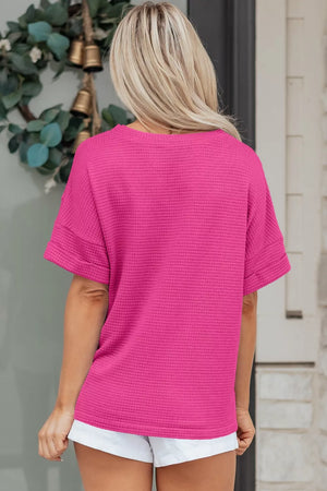 Hot pink waffle knit V-neck t-shirt with cuffed short sleeves.