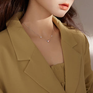 Sterling silver necklace with delicate chain and small circle pendant with red and white accents.