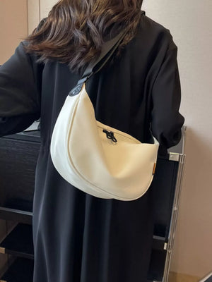 White crescent crossbody bag with adjustable strap and zipper closure.