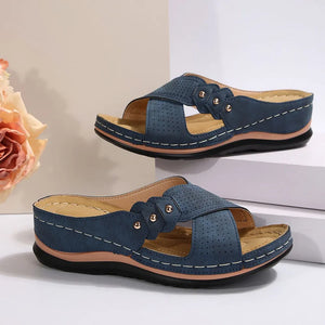 Perforated blue cross-strap comfort sandals with decorative studs and white stitching.