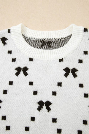White knit sweater with black diamond bow and square pattern, crew neck.