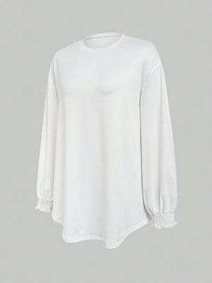 White oversized tunic top with long sleeves and ruffled cuffs.
