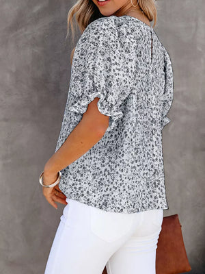 Maternity blouse with floral print, ruffle sleeves, and smocked bodice in a light color.