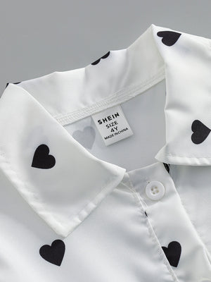 Baby dress with black heart print on white, button front detail.