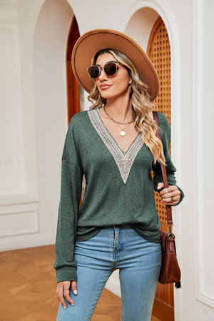 Green relaxed knit sweater with lace-trimmed V-neck and long sleeves.