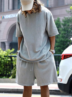 Men's light gray relaxed fit shorts with drawstring waist and raw hem detail.