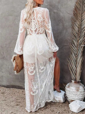 White floral lace maxi dress with long bell sleeves and a high slit, showing a sheer overlay.