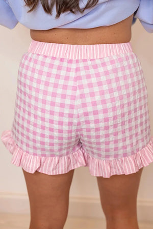 Blush pink gingham cotton shorts with ruffle hem and striped waistband.