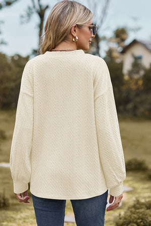Beige cable knit pullover sweater with textured pattern and long sleeves.