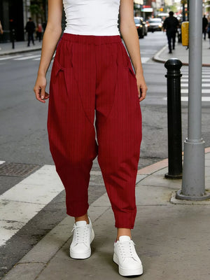 Burgundy harem pants with pockets and vertical pinstripes, styled with white sneakers.
