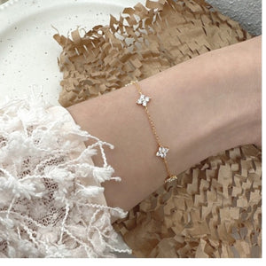 Gold bracelet with delicate four-leaf clover charms and crystal accents.