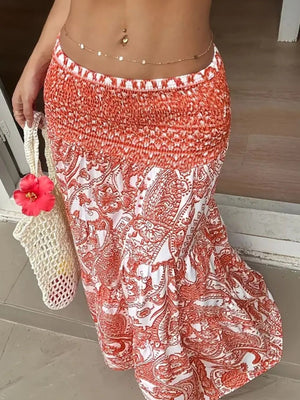 Bohemian maxi skirt in burnt coral paisley print with smocked waist, tiered hem, and flowy silhouette.
