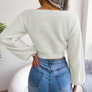 White ribbed knit crop top with balloon sleeves and a V-neckline, styled with jeans.