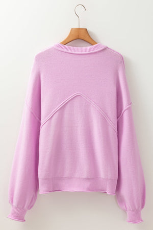 Pink knit sweater with puffed sleeves and contrast stitching detail on the back.