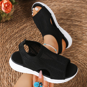 Black mesh open-toe sandals with a chunky white sole and ankle strap.
