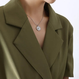 Silver coin necklace with sun and moon detail, styled with a green blazer.