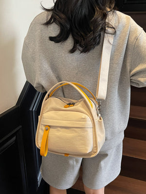 Khaki crossbody bag with yellow accents and decorative pull tab