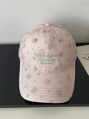 Pink floral embroidered baseball cap with "Weekend Calling Company" text.