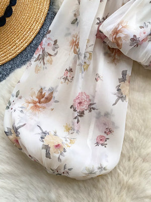Chiffon floral blouse with balloon sleeves and a cropped hem, styled with a straw hat.