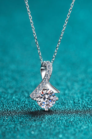 Silver solitaire pendant necklace with diamond-accented ribbon detail.