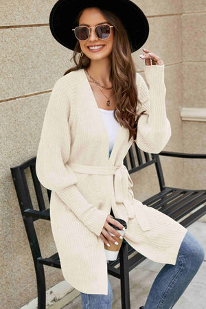 Cream knit cardigan with puffed sleeves and a tie belt, made of acrylic.