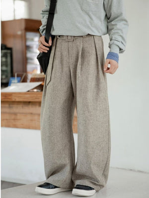 Men's wide leg trousers in beige with pleats and belt detail.