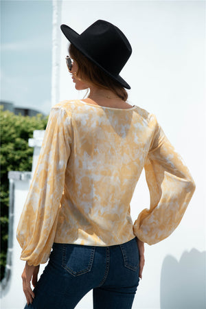 Tie-front blouson top in light yellow with swirl print and balloon sleeves.