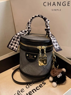 Quilted mini bucket bag in black with checkered scarf detail and fuzzy charm.