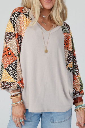 Light gray v-neck top with patchwork raglan sleeves in animal print patterns.