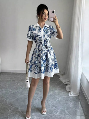 Indigo floral print mini dress with tie belt, collared, short sleeves, and a flared skirt.