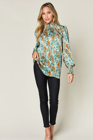 High neck abstract print blouse in green with smocked neckline and cuffs, long sleeves.
